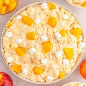 Large bowl of Peach Fluff topped with peaches and mini marshmallows.