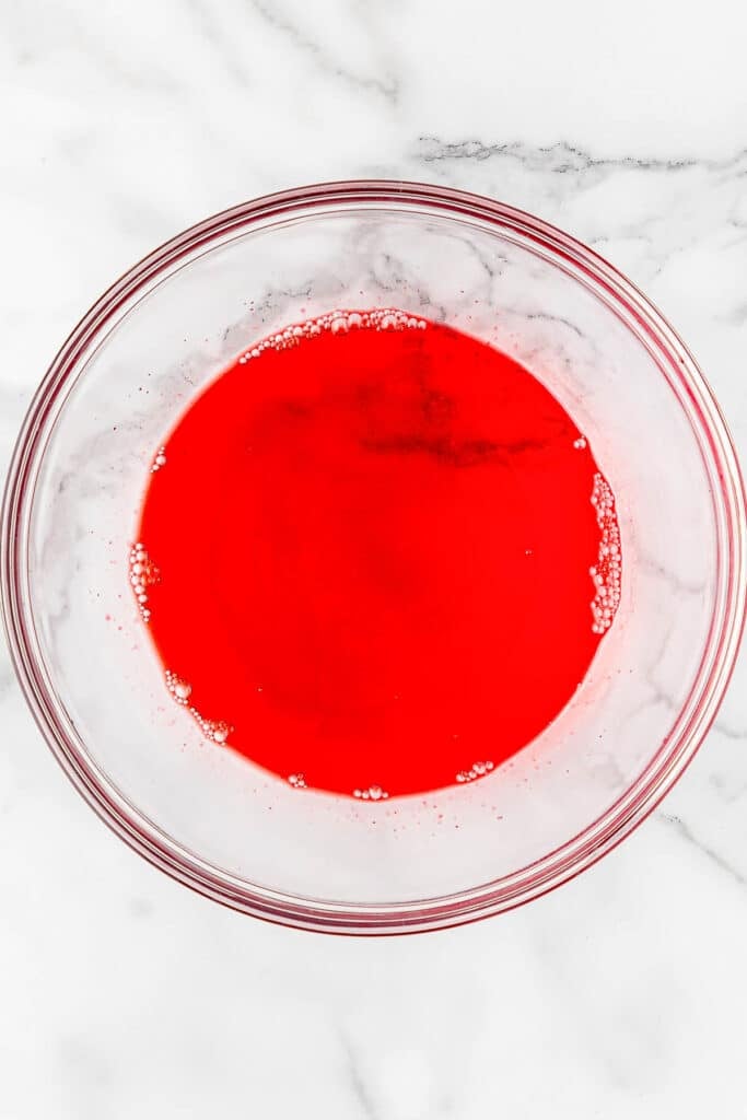 Strawberry jello mix in glass mixing bowl.