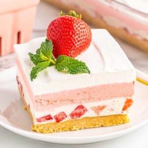 Slice of strawberry delight on white plate.