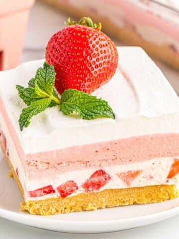 Slice of strawberry delight on white plate.
