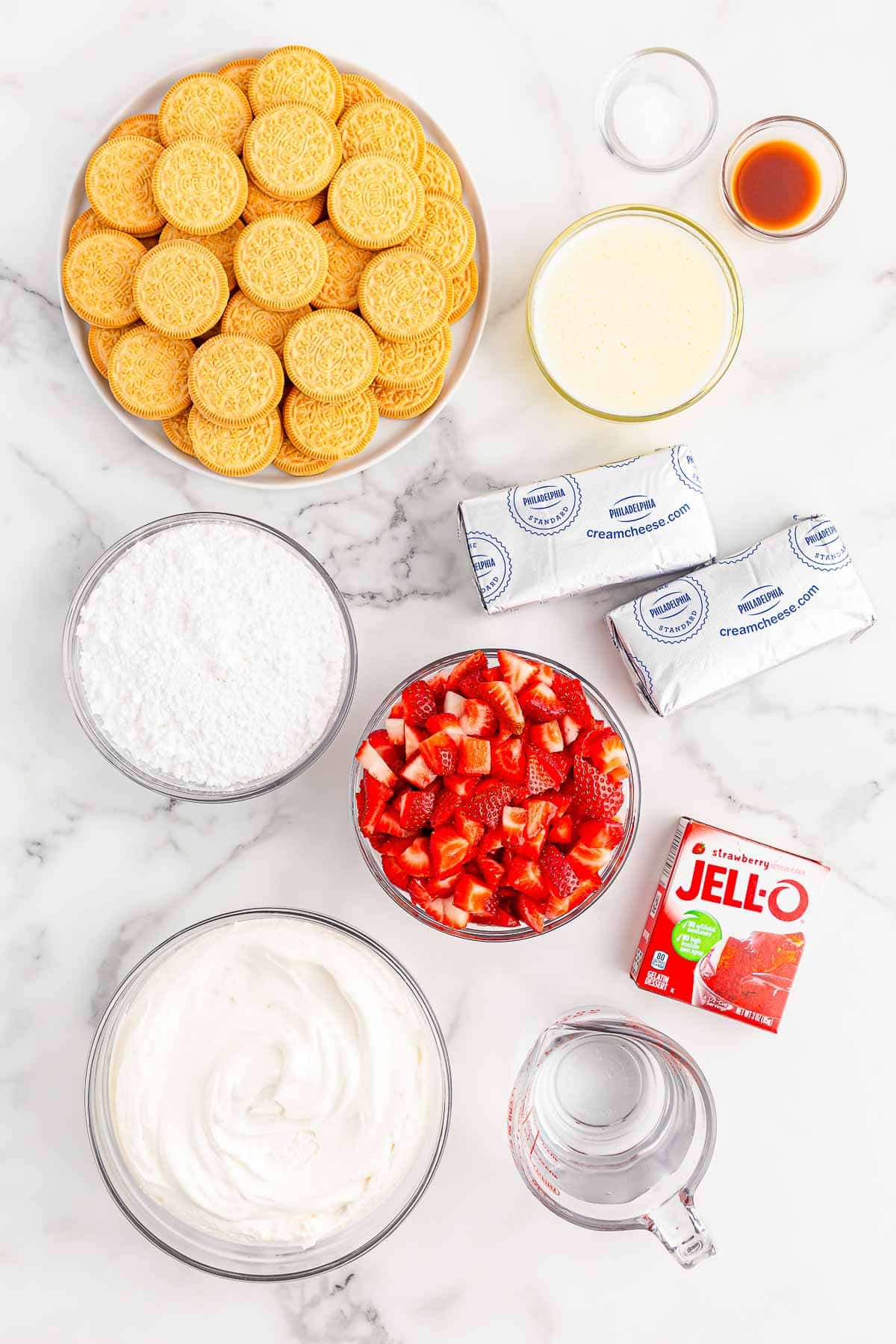 Ingredients for Strawberry delight - strawberries, strawberry jello, water, cool whip, powdered sugar, cream cheese, golden oreos, vanilla extract and salt.