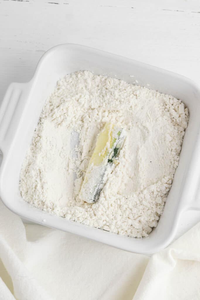 Zucchini strip in flour mixture.