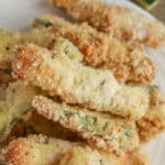 stack of crispy baked zucchini fries on a white plate.