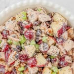 Chicken salad with grapes, cranberries and walnuts in a big white bowl.