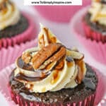 Turtle Cupcake topped with pecans, chocolate and caramel sauce in a pink cupcake liner.