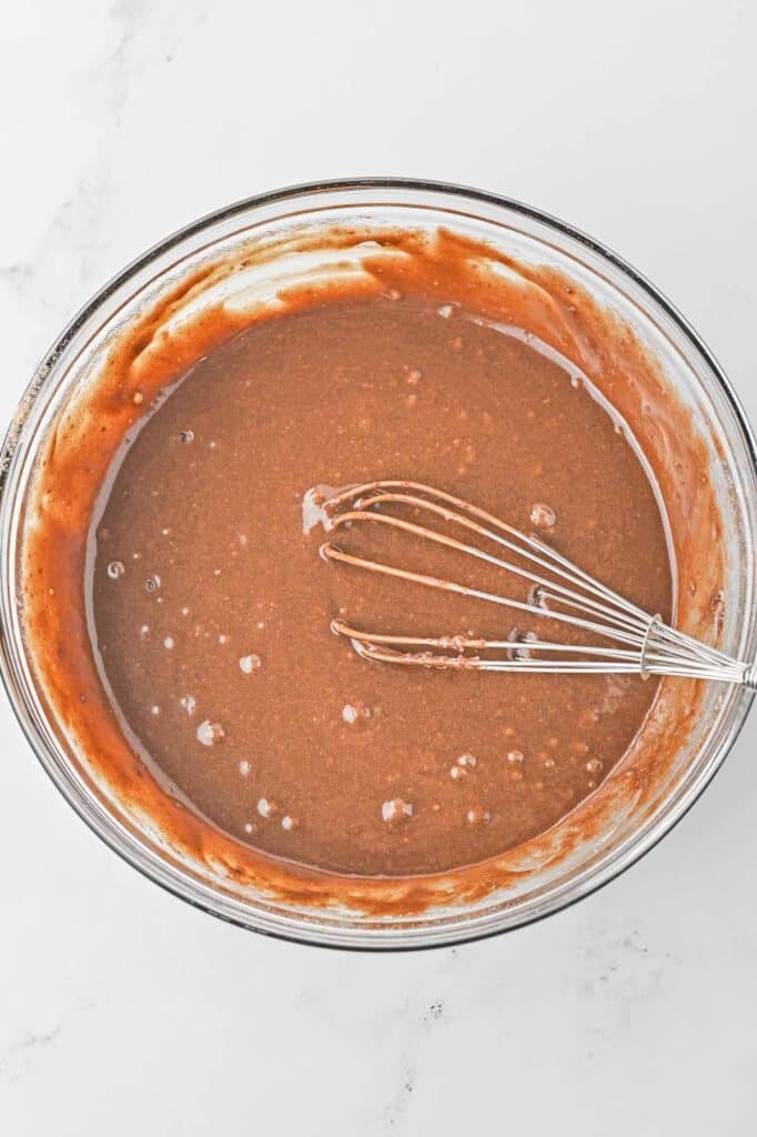 A bowl of chocolate pudding with a whisk in it.