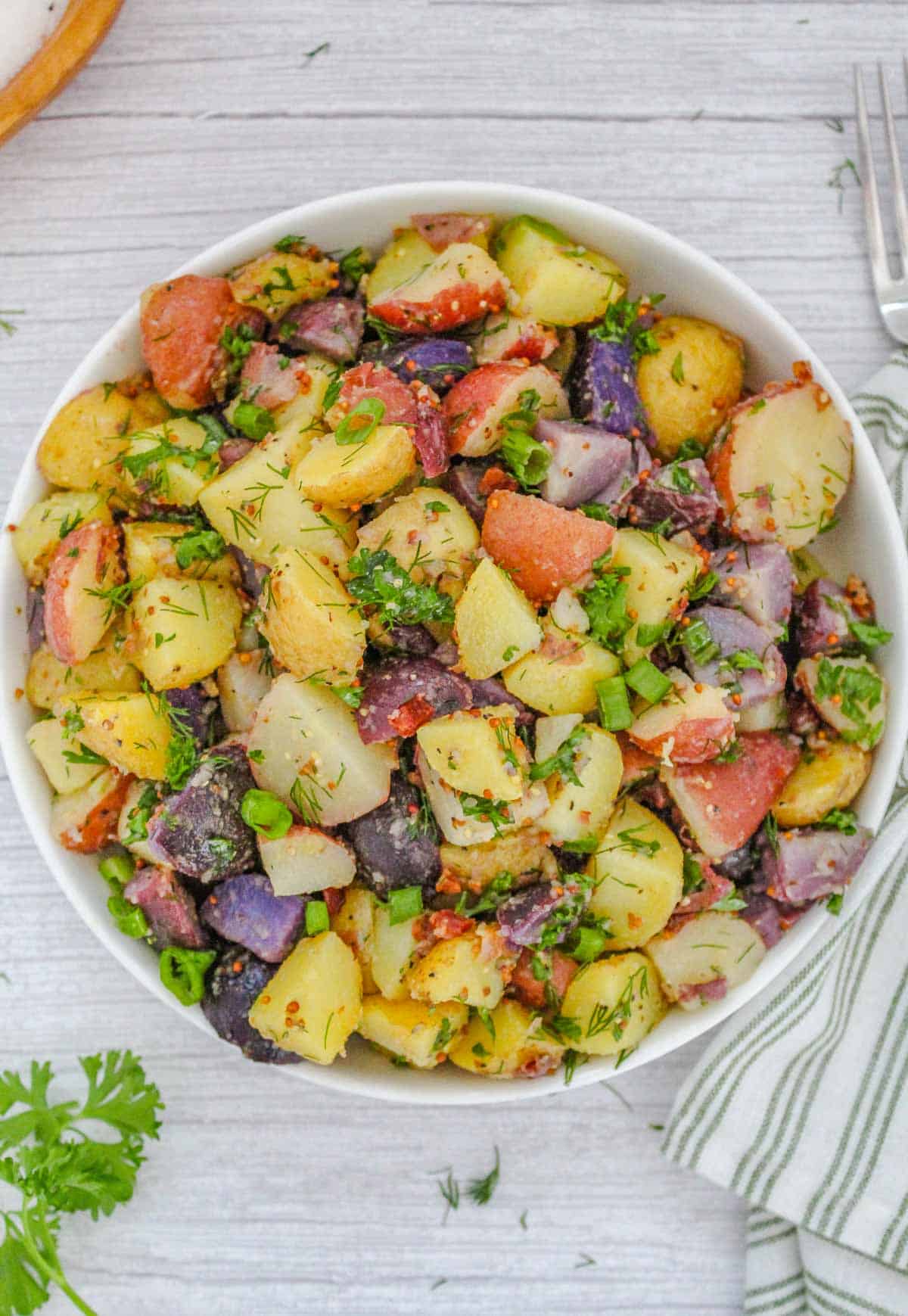 german Potato salad with no mayo topped with fresh herbs in a white bowl.