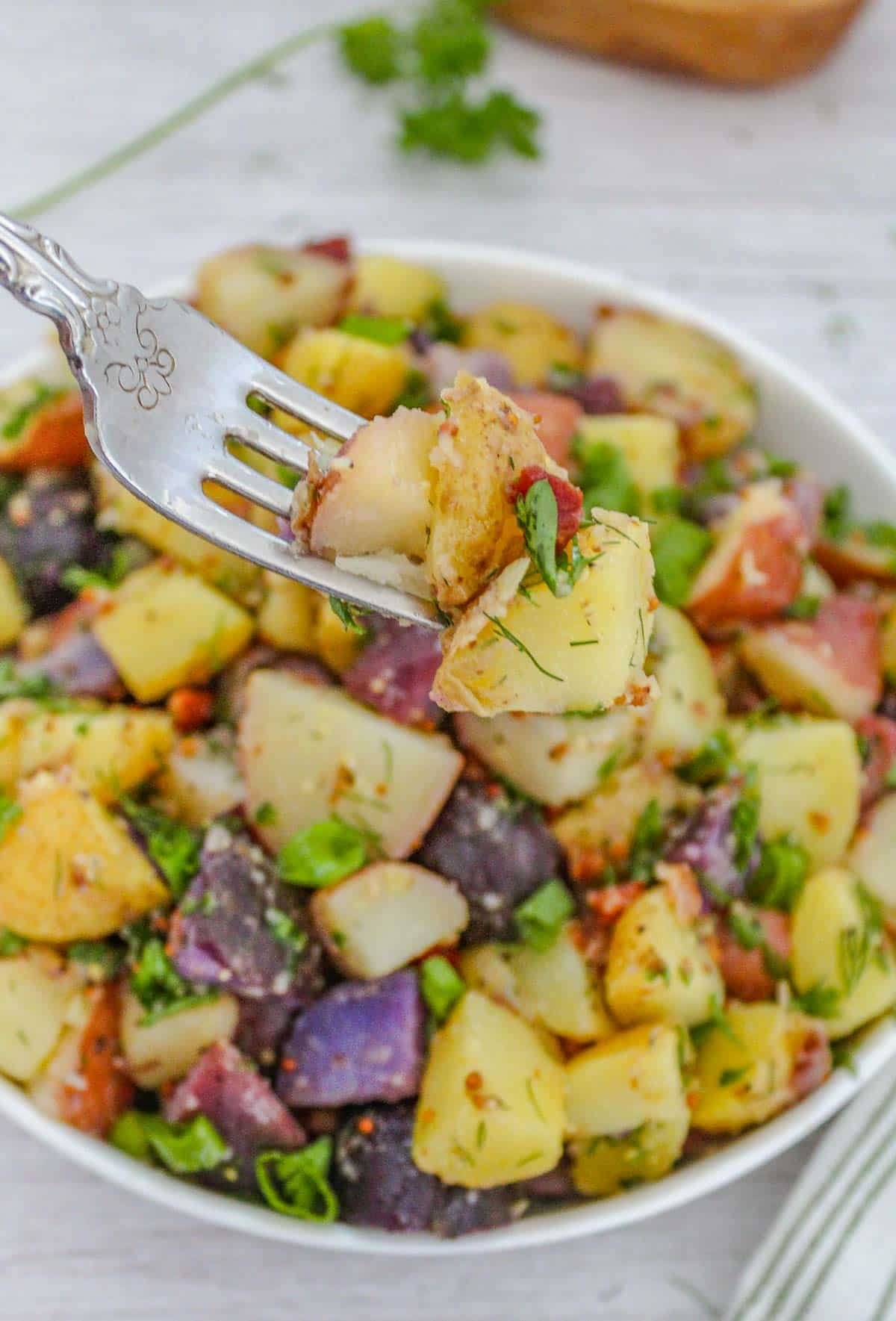 A bowl of german potato salad with a fork picking up cubes of potatoes.