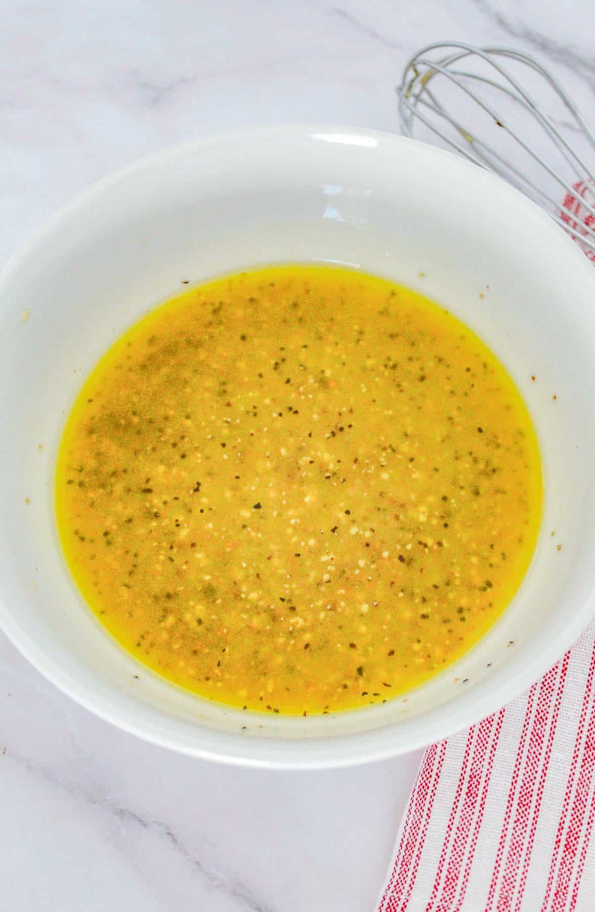 A bowl with a yellow sauce and a whisk.