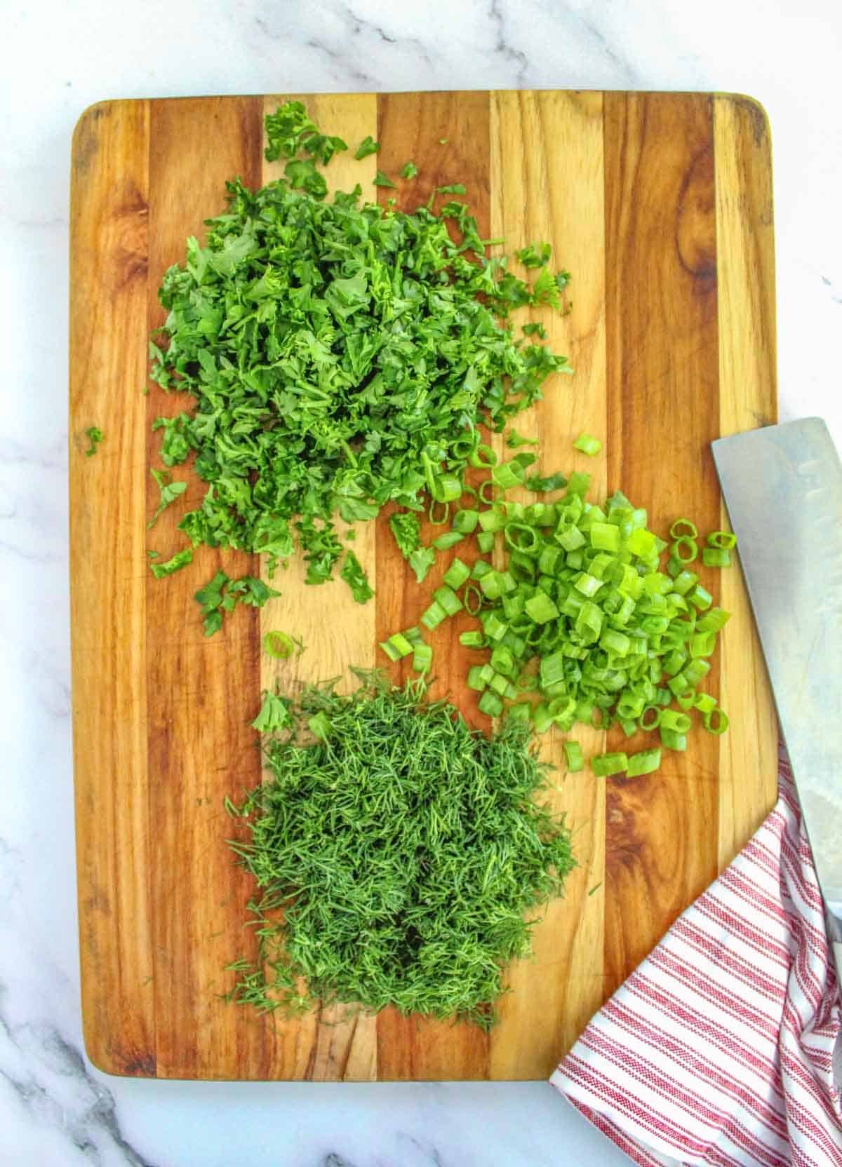 Chopped chives on a cutting board with a knife.