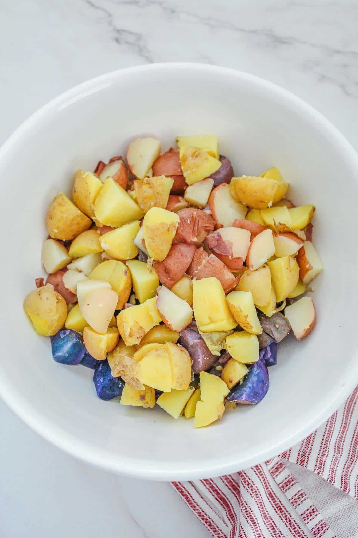 diced potatoes in a white bowl with a red and white striped napkin.