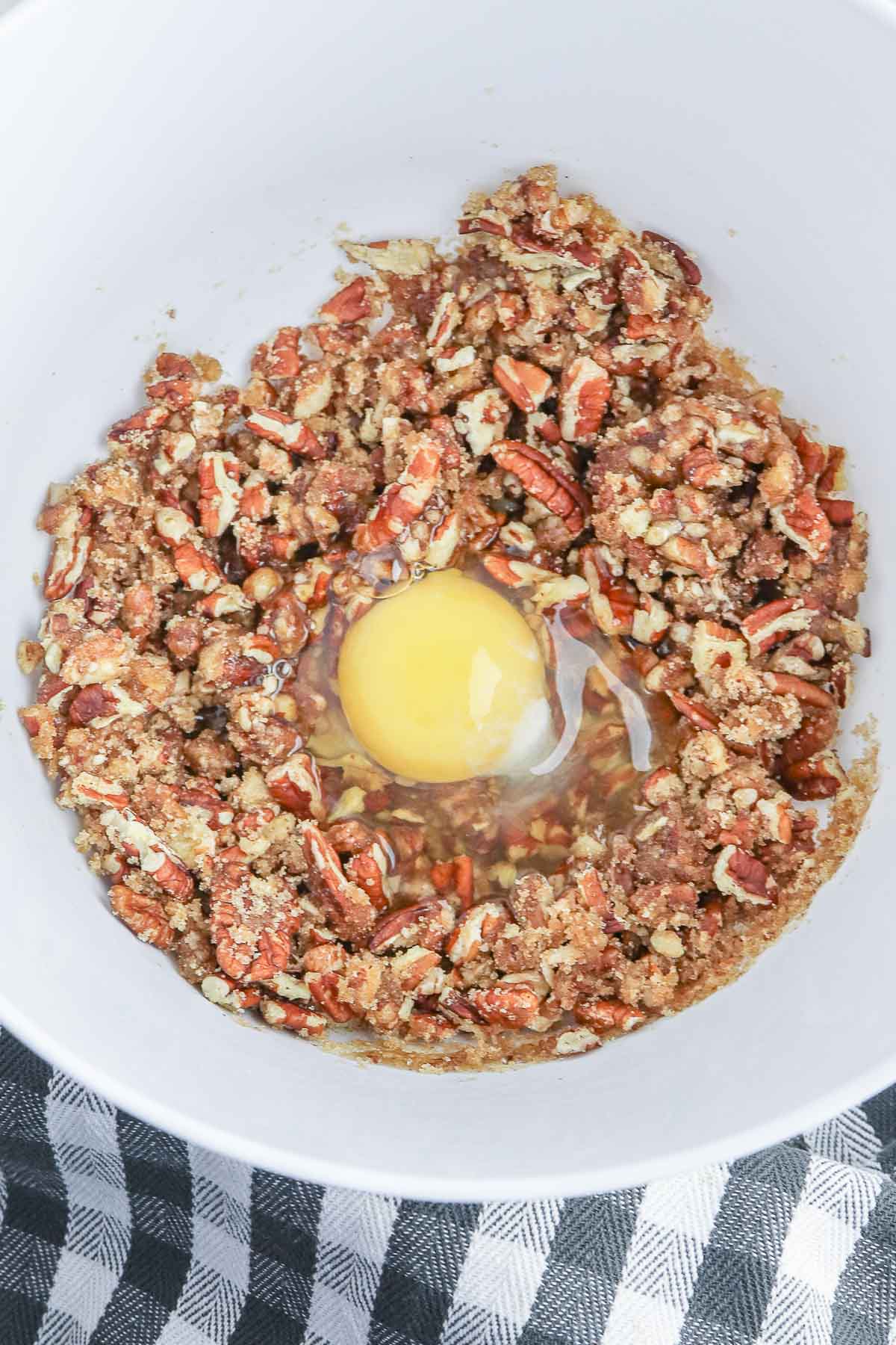 A white bowl with an egg and chopped pecans.