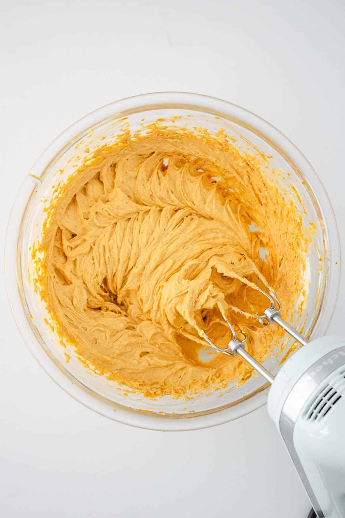 A mixer is being used to make pumpkin cheesecake batter.