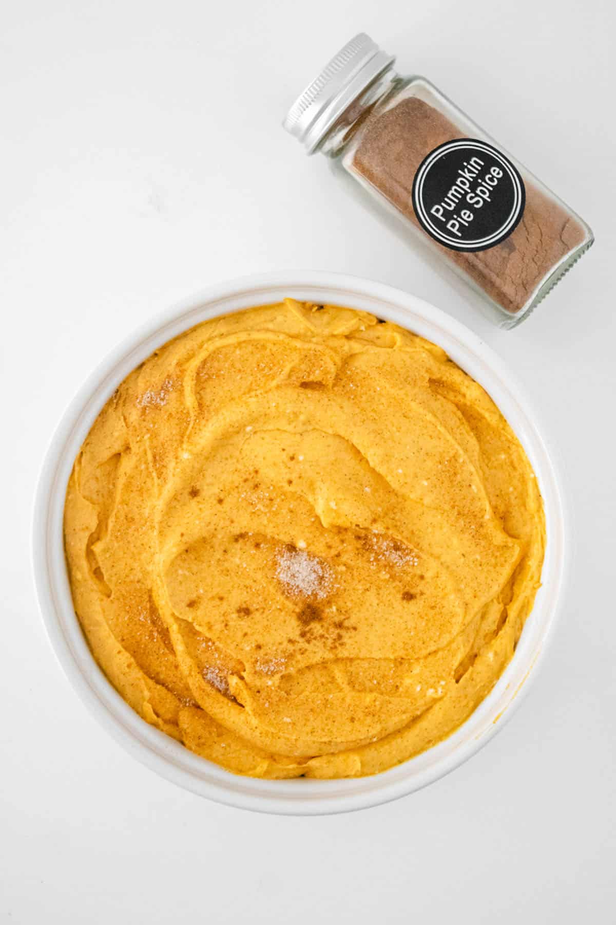 Pumpkin cheesecake dip in a white bowl topped with pumpkin pie spice.