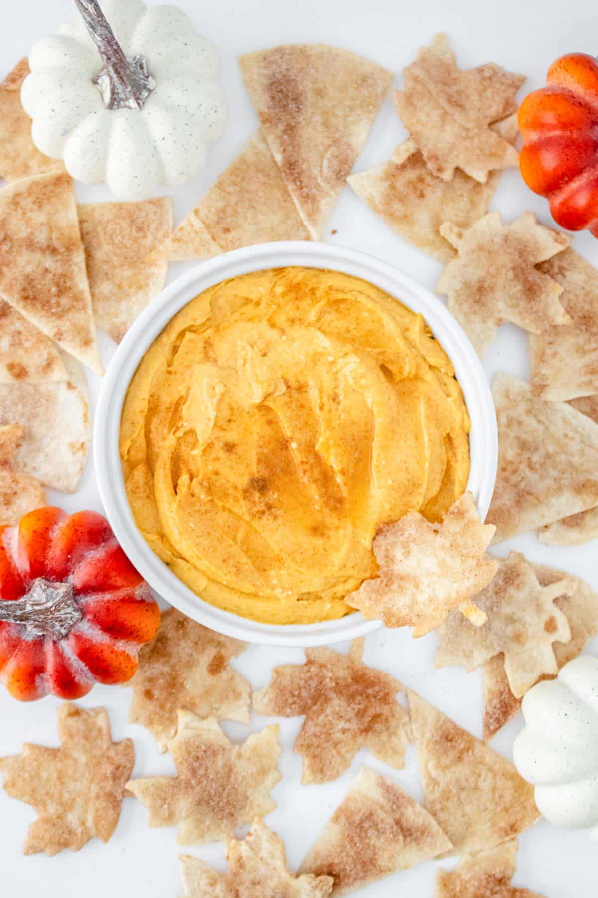 A bowl of pumpkin cheesecake dip surrounded by tortilla chips.
