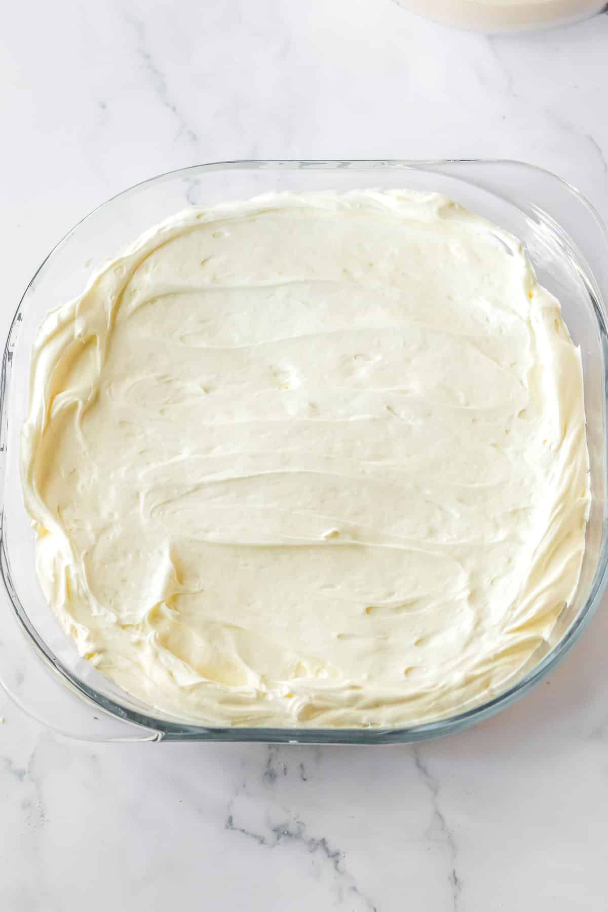 A glass baking dish with whipped topping.