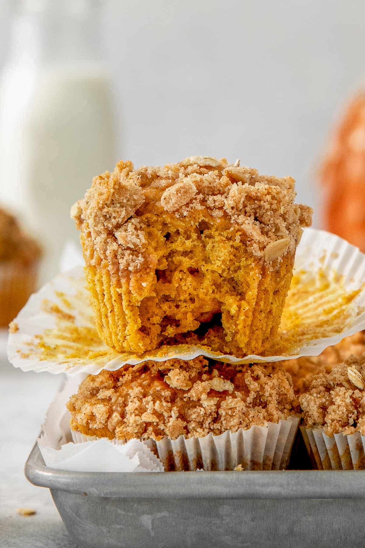 A stack of pumpkin oat muffins with a bite taken out of them.