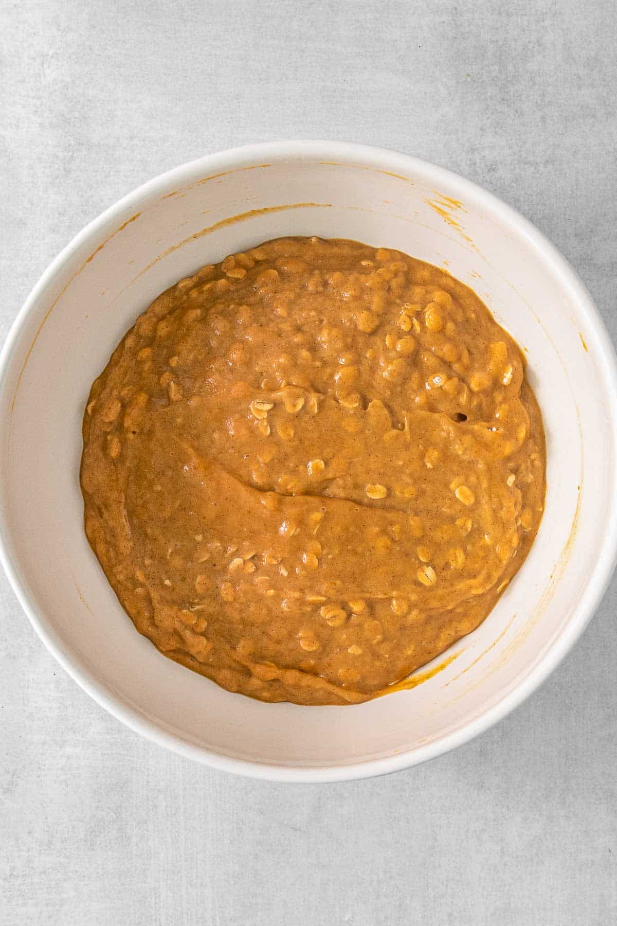 A white bowl filled with a pumpkin oat batter.