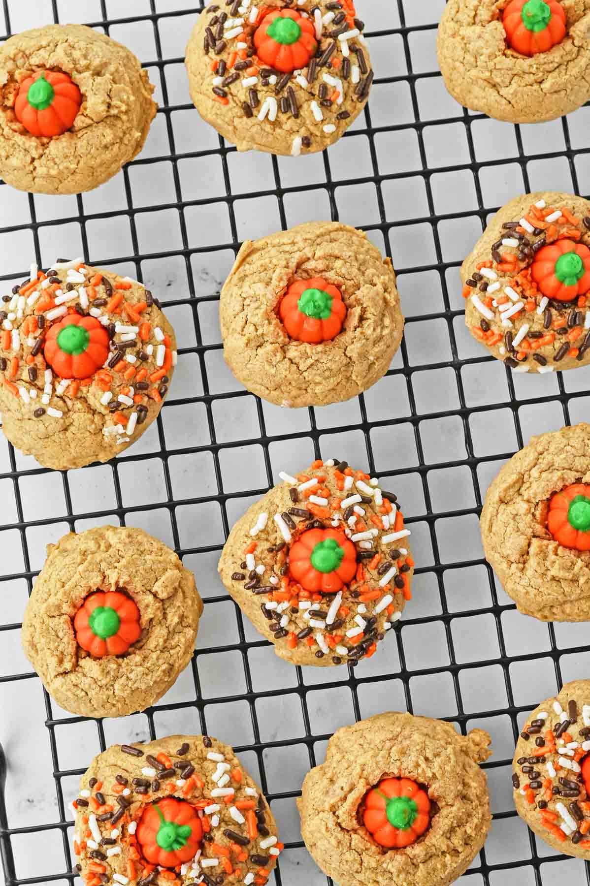 Pumpkin spice cookies on a cooling rack with sprinkles and pumpkin.