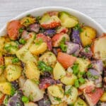 german Potato salad with no mayo topped with fresh herbs in a white bowl.