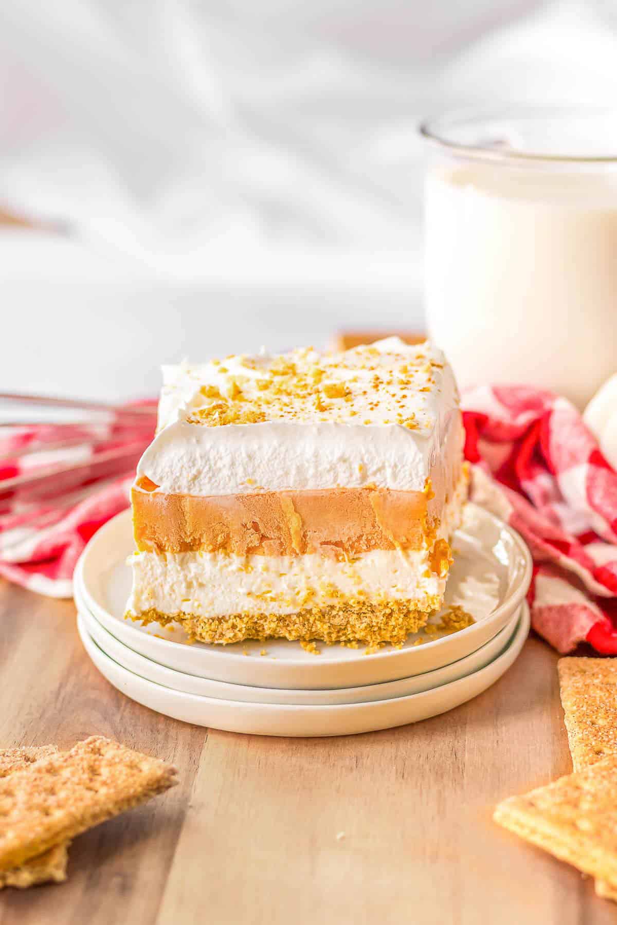 A white plate with a piece of pumpkin lush cake
next to a glass of milk.