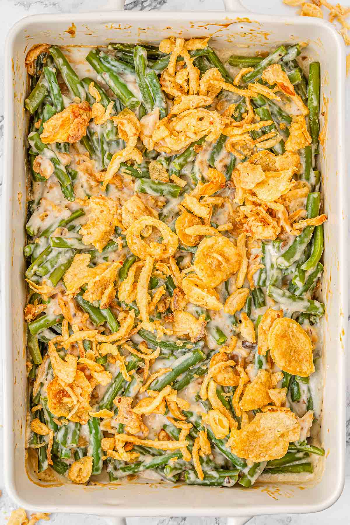 Green bean casserole in a white casserole dish topped with fried onions.