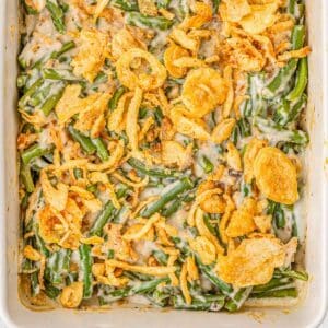 Green bean casserole in a white casserole dish topped with fried onions.