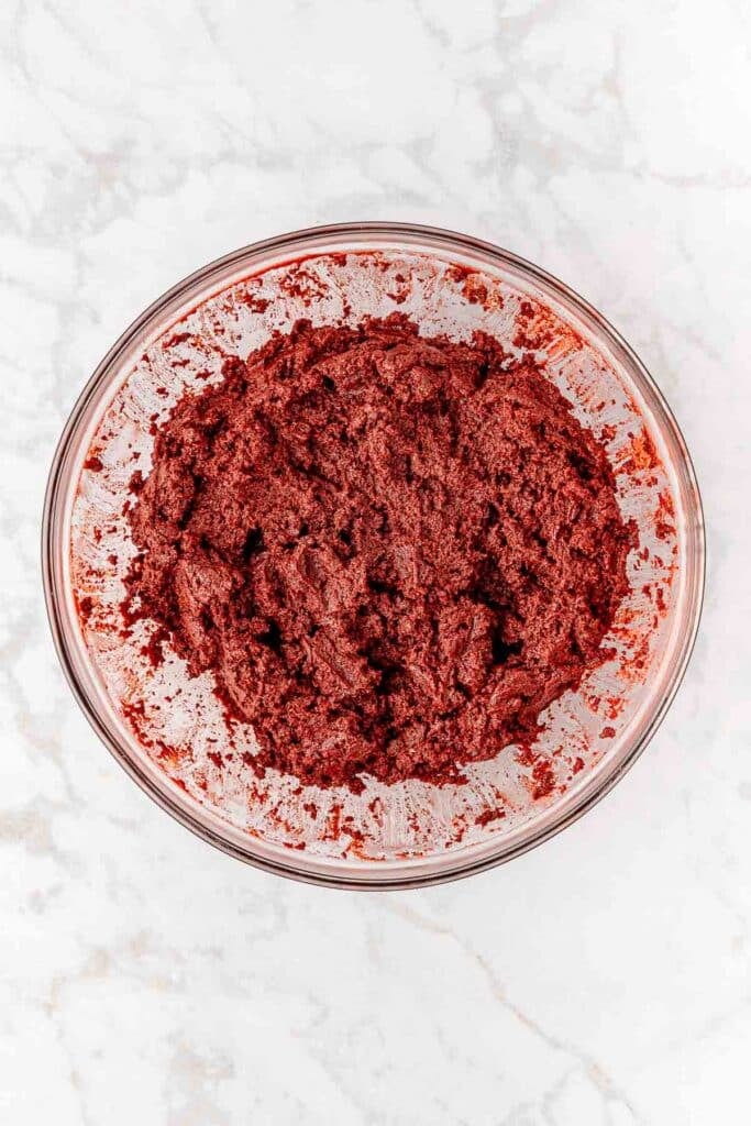 Red velvet oreo ball batter in a glass bowl on a marble countertop.