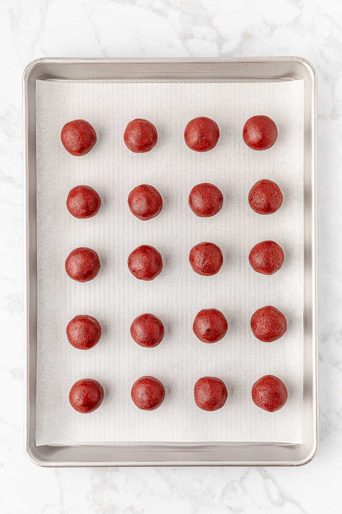 24 red velvet oreo balls on a baking sheet.