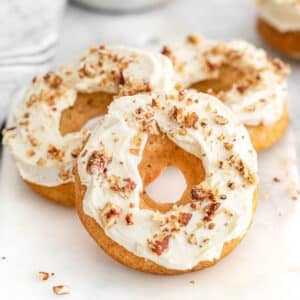 Several maple donuts topped with pecans on a white tray.