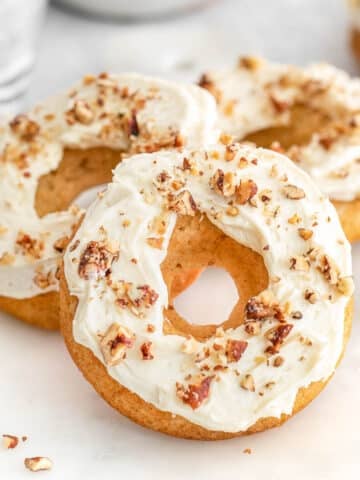 Several maple donuts topped with pecans on a white tray.