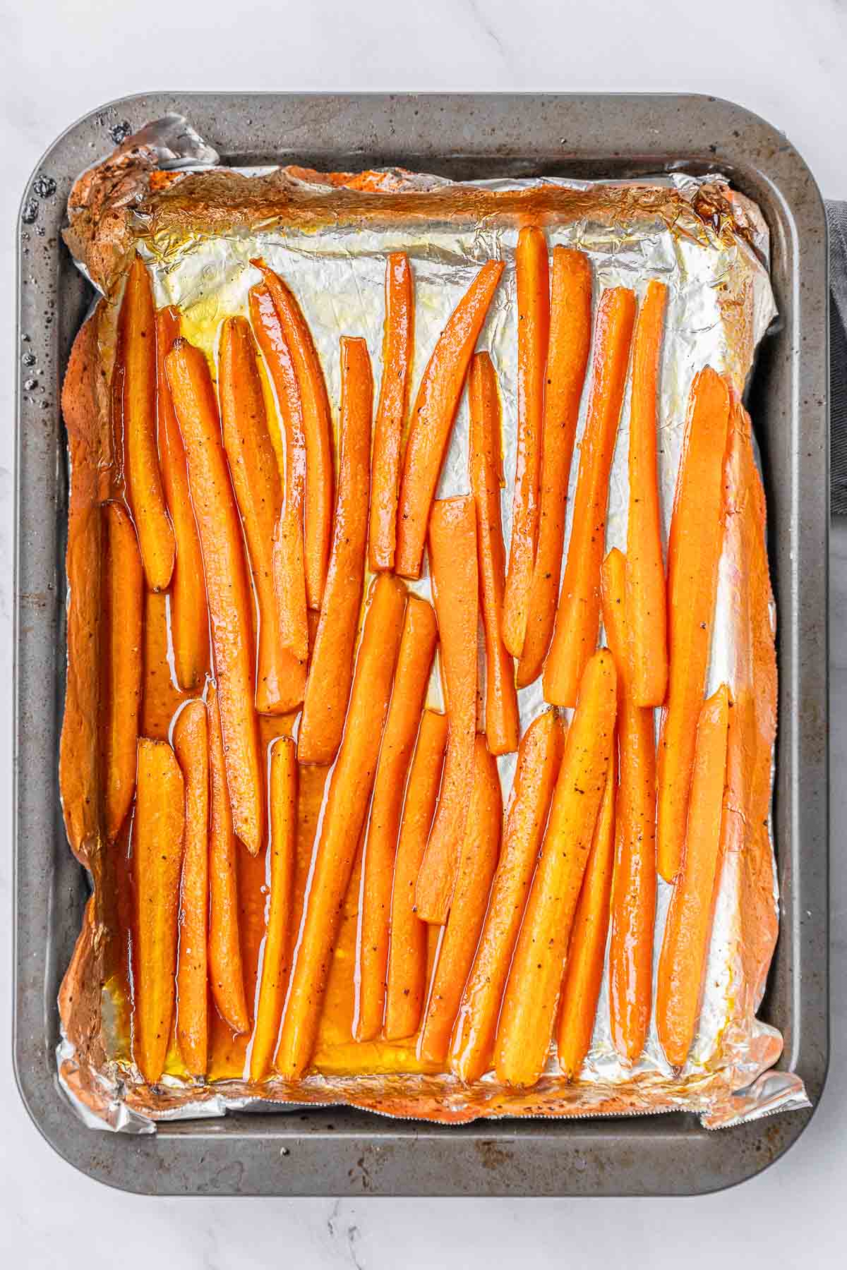Glazed roasted carrot slices on a baking sheet.