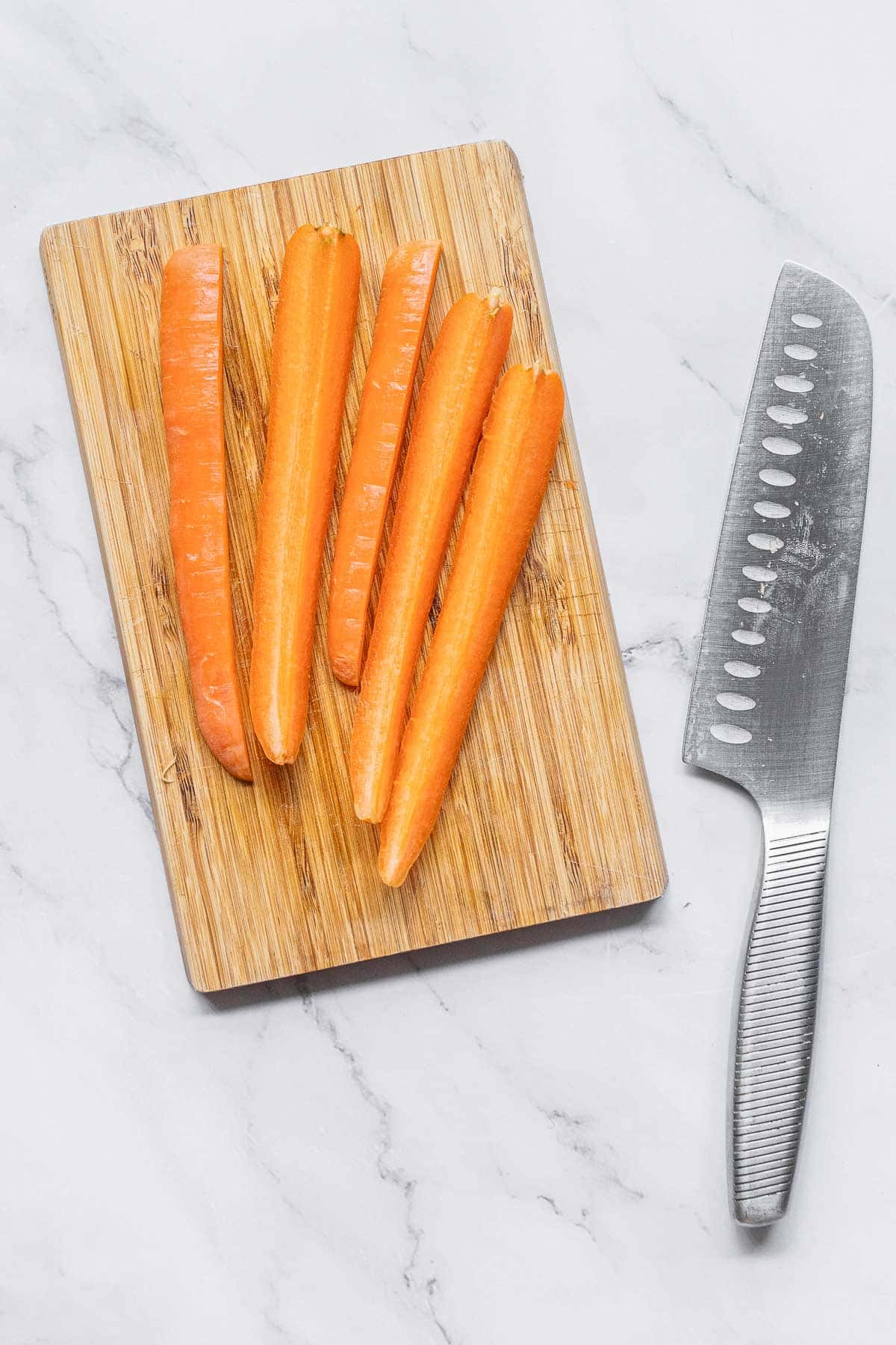 Carrots on a cutting board next to a knife.