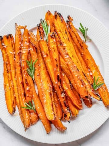 Maple Glazed Carrots on a white plate with rosemary.