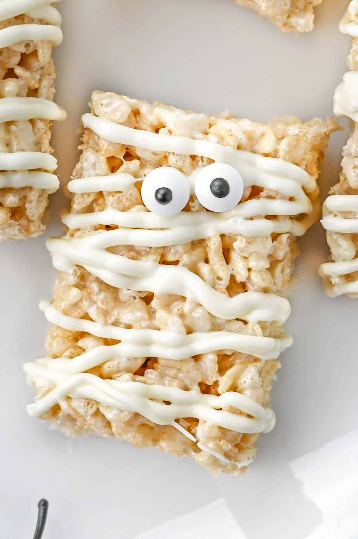 closeup of a Mummy rice krispy treat white candy eyes on a white plate.