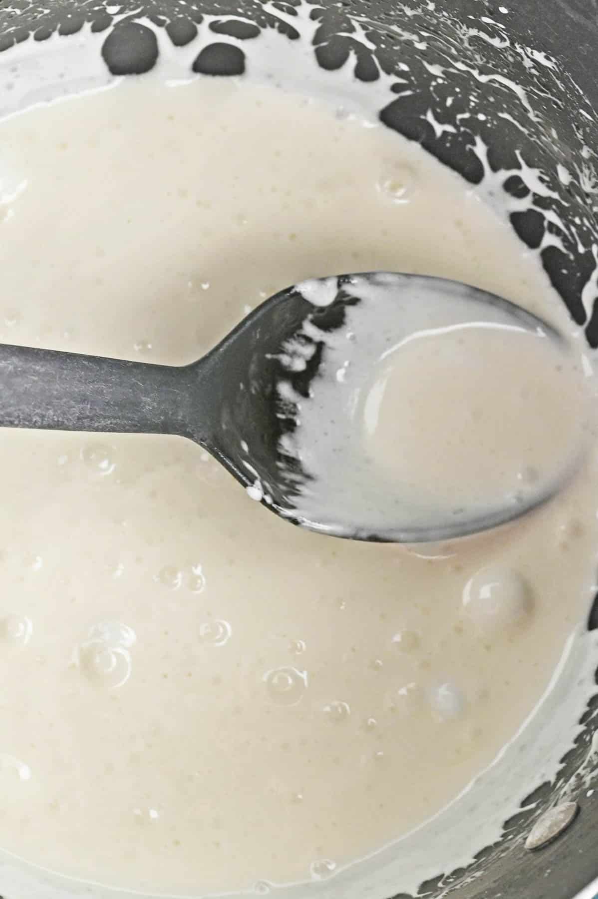 A spoon is being used to stir a bowl of melted white candy wafers.