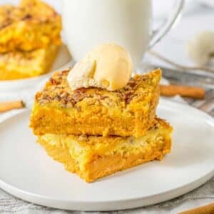 Pumpkin crunch cake topped with vanilla ice cream on a white plate.