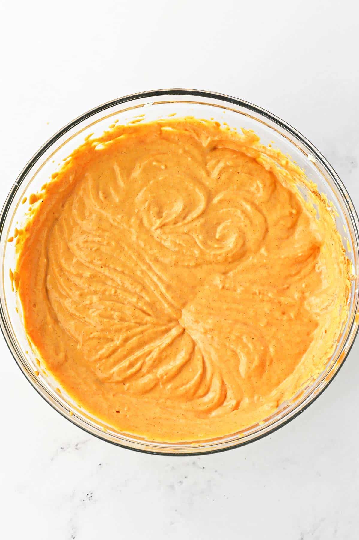 Pumpkin cheesecake mixture in a large glass bowl.