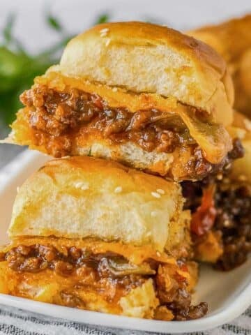 Multiple Sloppy Joe sliders stacked on a white plate.