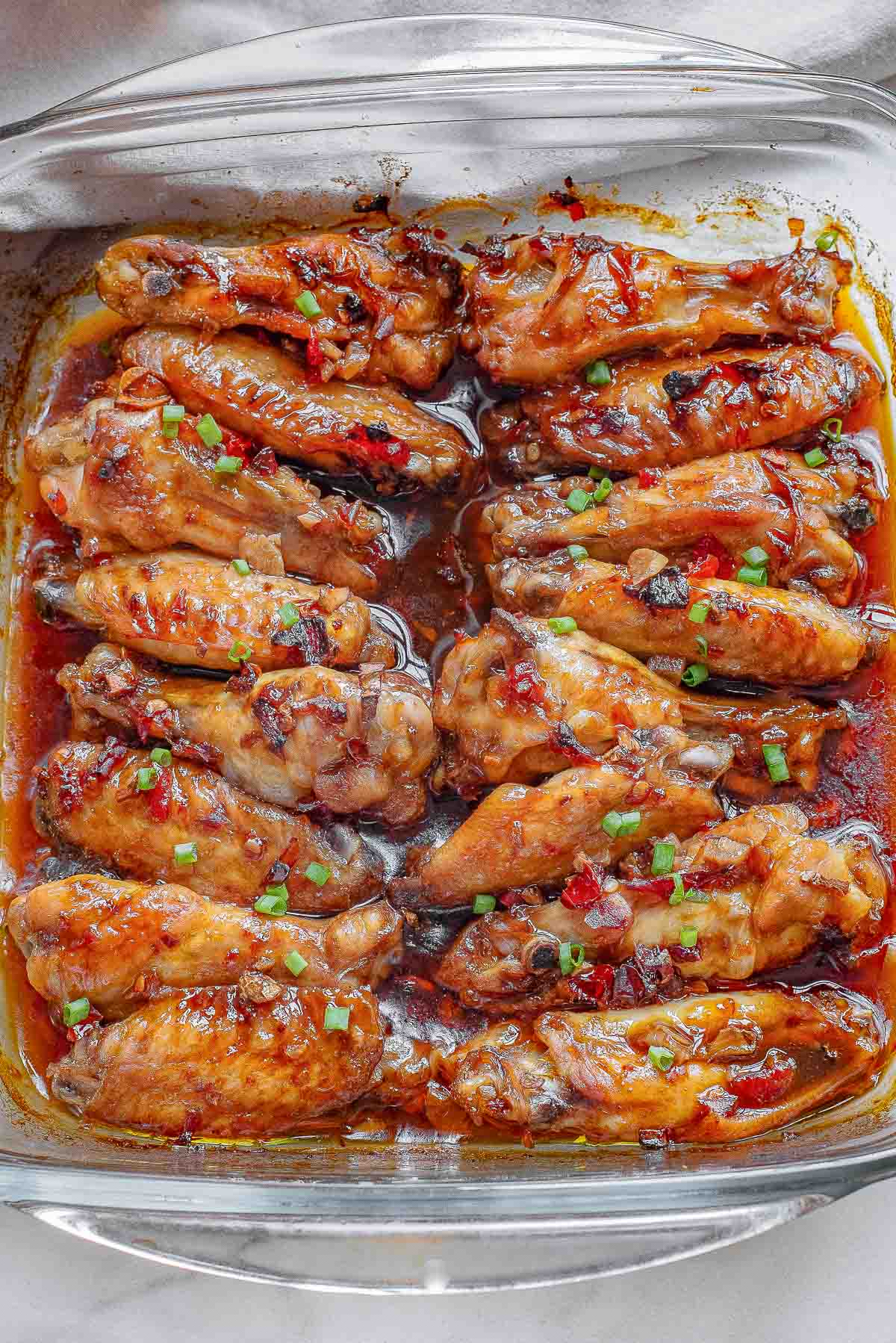 Thai chicken wings laid in a large glass baking dish.