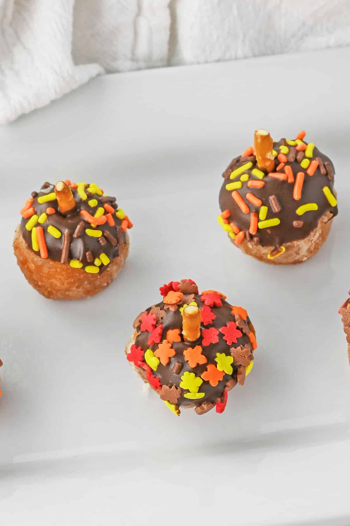 acorn donut holes decorated with chocolate and sprinkles on a plate.