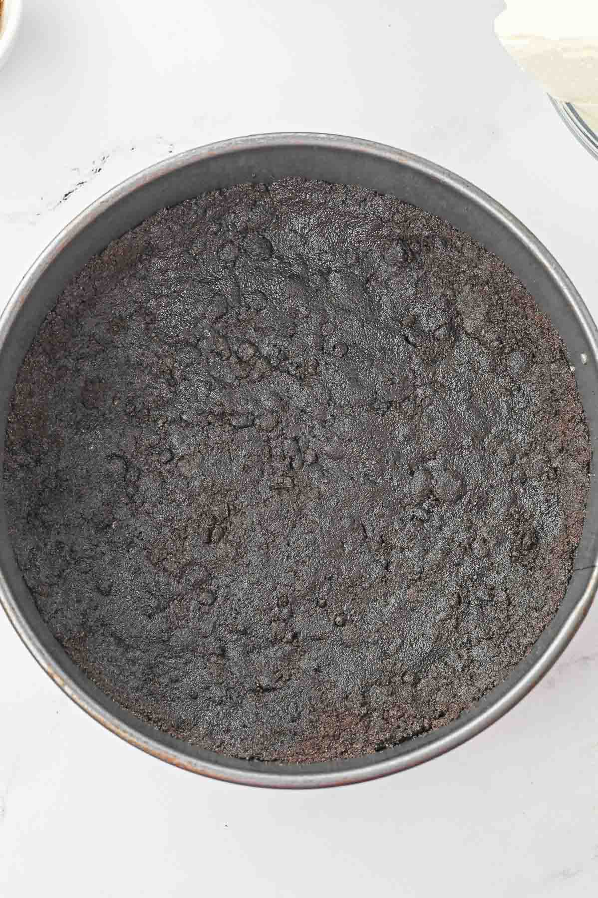 Oreo cookie crumb mixture pressed on bottom of cooking pan.