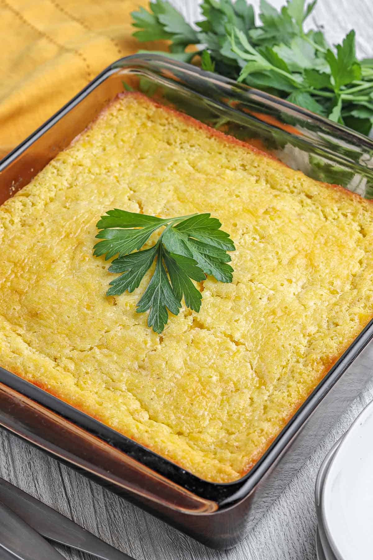 Corn casserole with parsley in a baking dish.