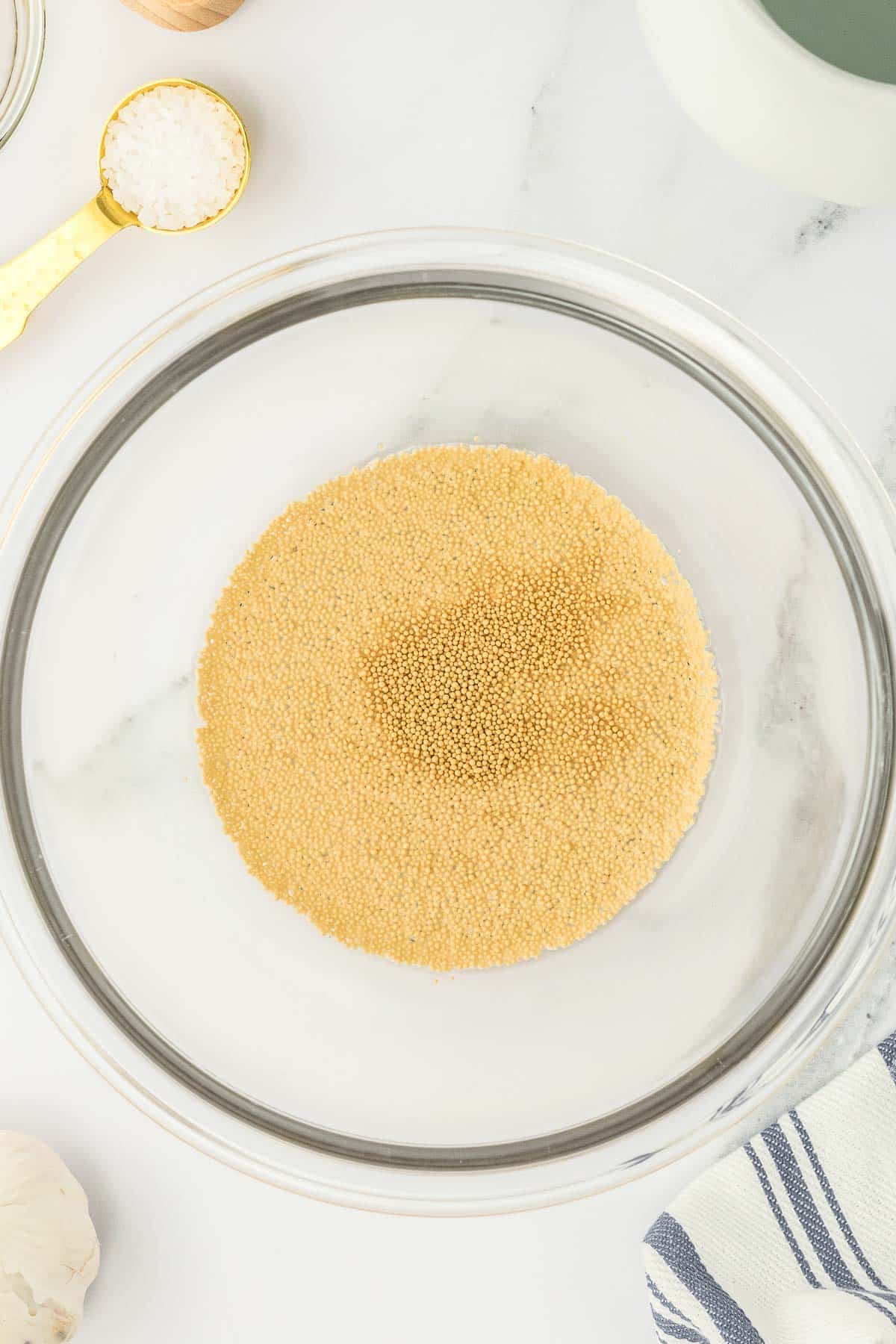 A large glass bowl containing yeast mixture.