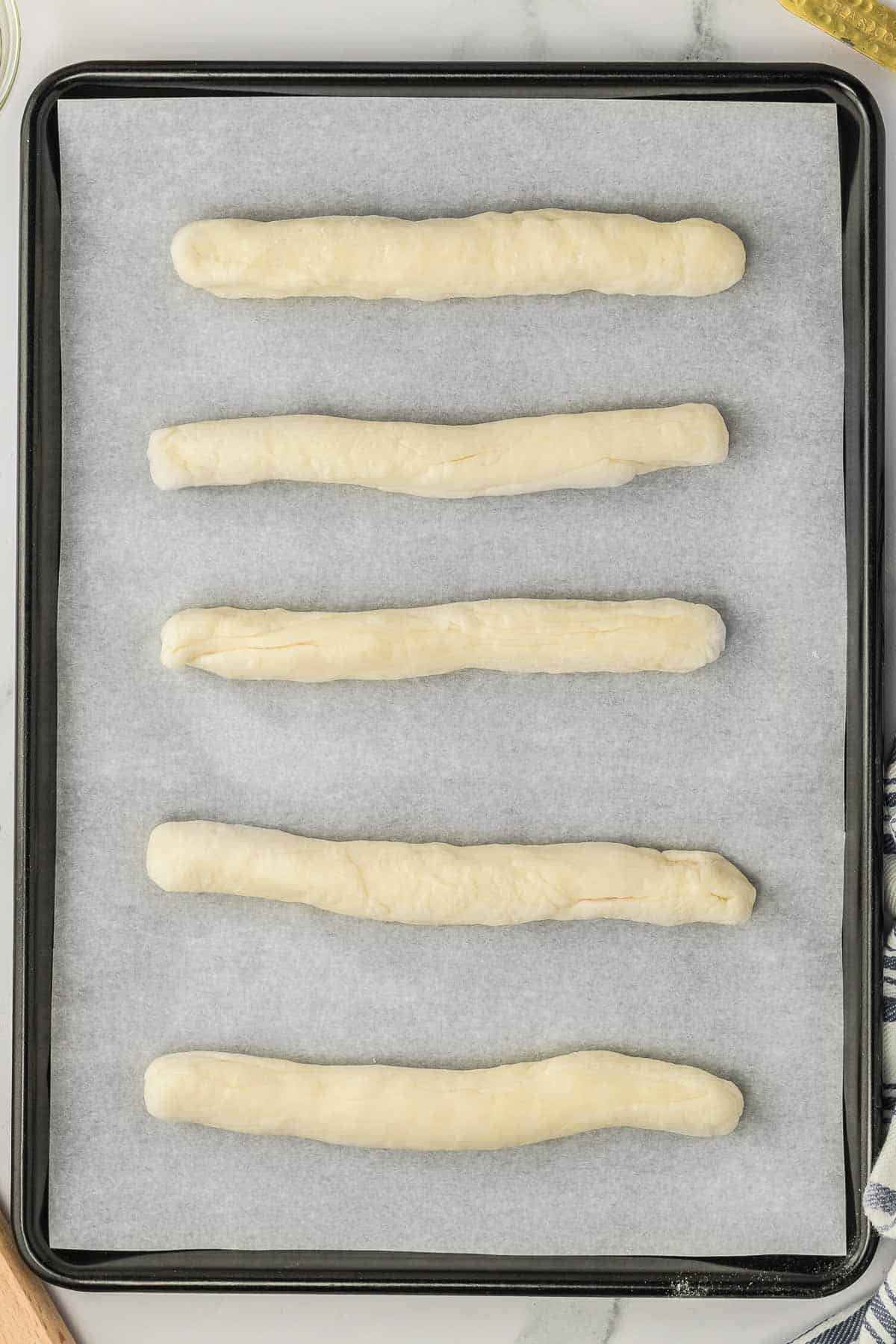 A baking sheet with rolled bread dough on it.