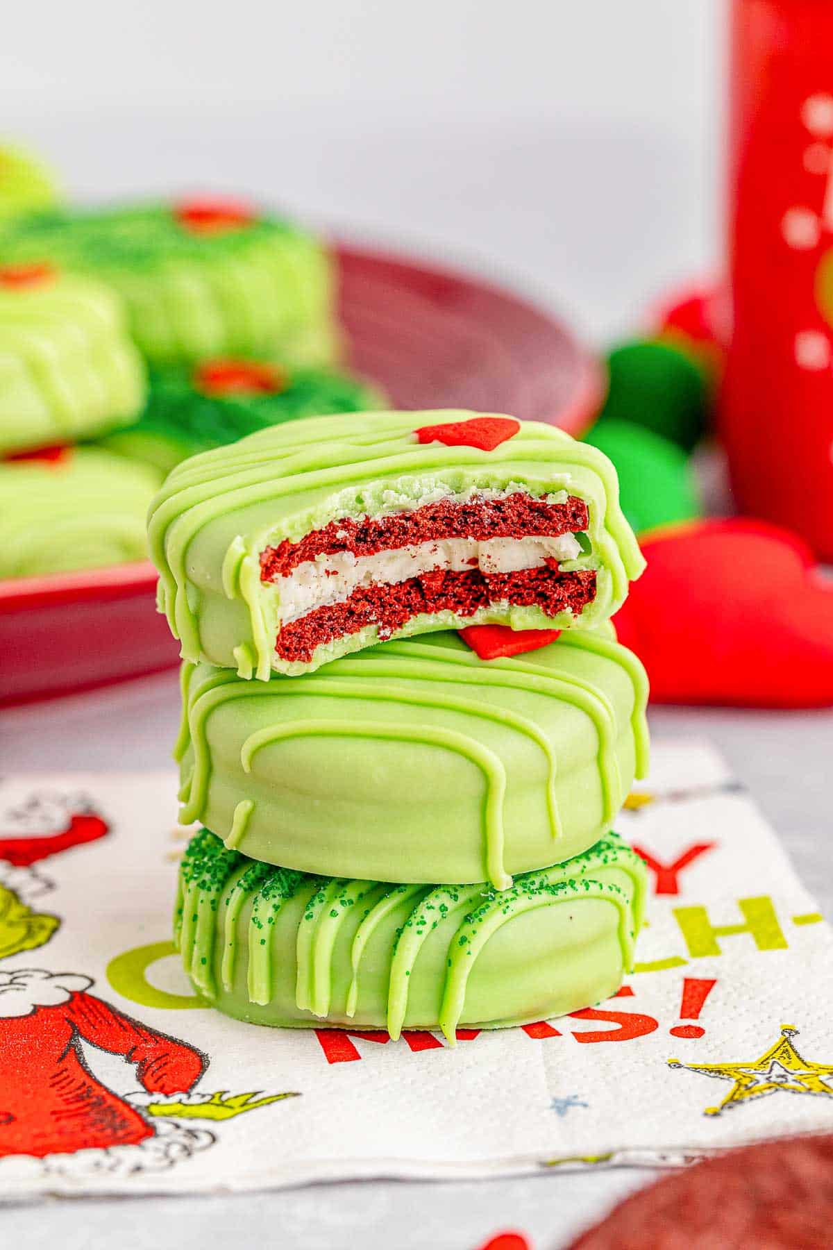 A stack of grinch oreos on a holiday napkin.
