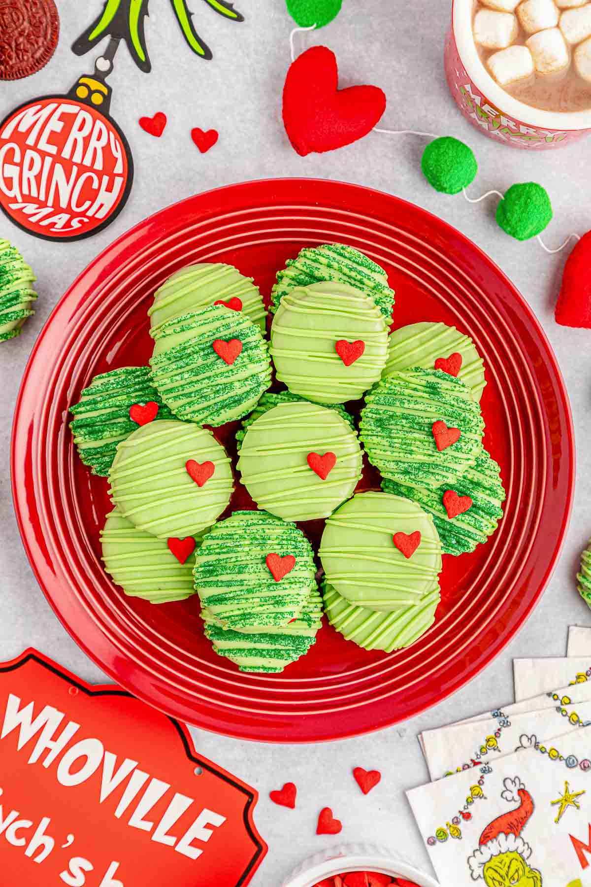 A red plate of several grinch oreos with a heart shaped candy on it.
