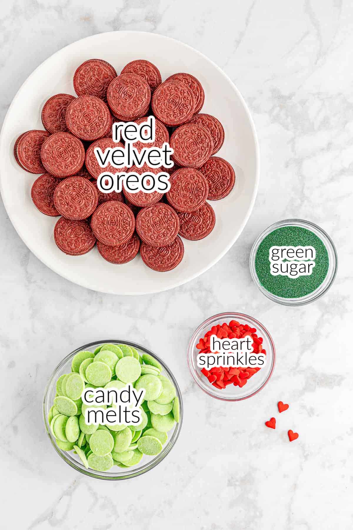 Ingredients for grinch oreos - red velvet oreos, green sugar, candy melts and heart sprinkles.