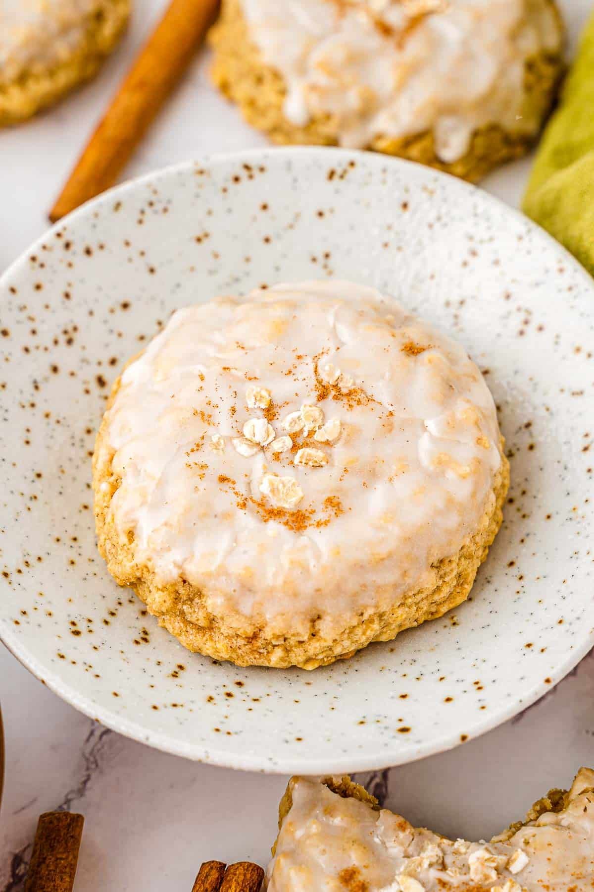A plate with an iced oatmeal cookie on it.