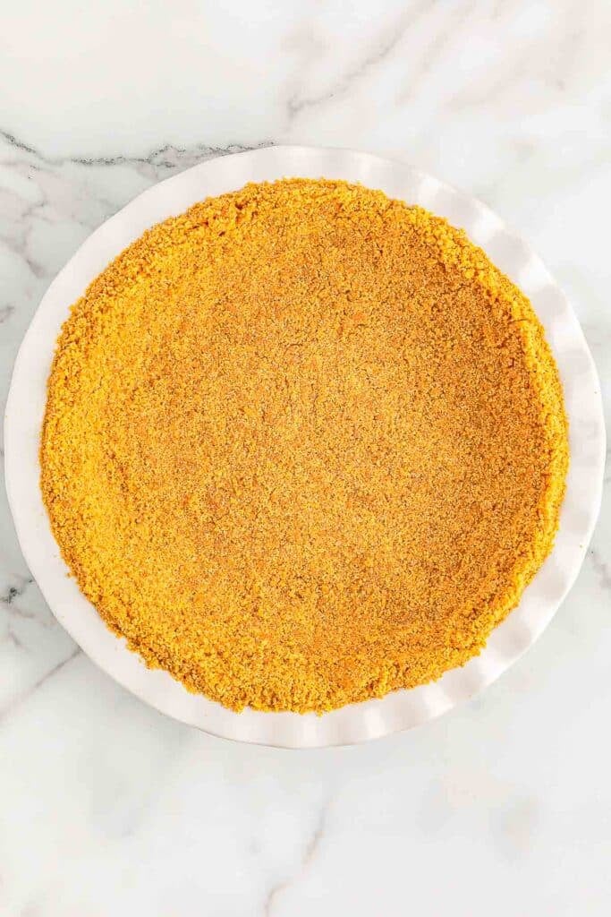 Graham cracker crumb crust spread in a white pie pan.